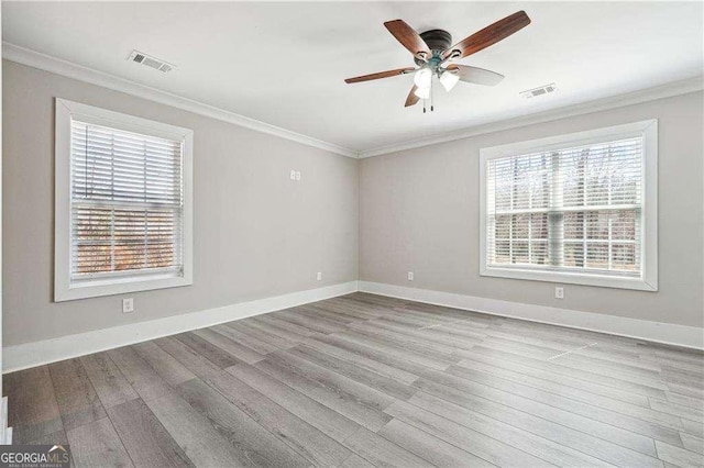 unfurnished room featuring visible vents, wood finished floors, and ornamental molding