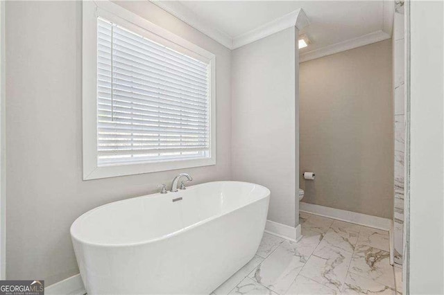 bathroom with crown molding, baseboards, toilet, a soaking tub, and marble finish floor