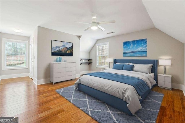 bedroom featuring visible vents, baseboards, vaulted ceiling, wood finished floors, and a ceiling fan