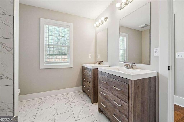 bathroom featuring a sink, baseboards, two vanities, and marble finish floor