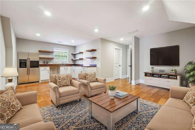 living room featuring recessed lighting, baseboards, and light wood-style flooring