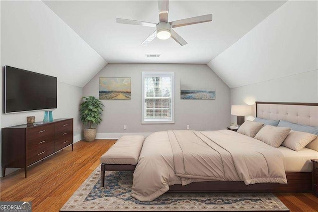 bedroom with visible vents, a ceiling fan, wood finished floors, baseboards, and vaulted ceiling