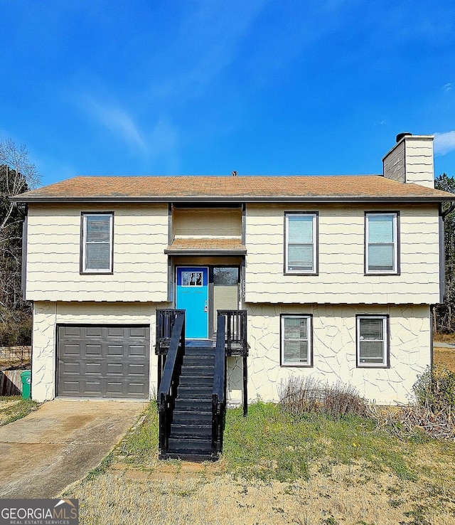 split foyer home with driveway, a chimney, and a garage