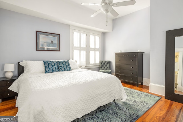 bedroom featuring baseboards, wood finished floors, and a ceiling fan