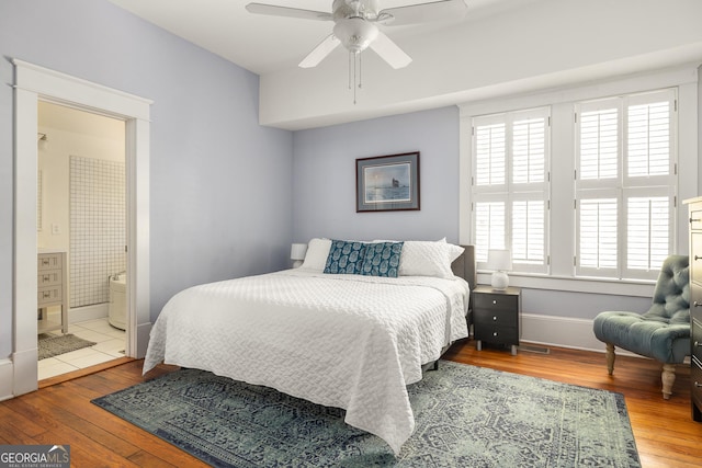 bedroom featuring hardwood / wood-style floors, a ceiling fan, baseboards, and connected bathroom