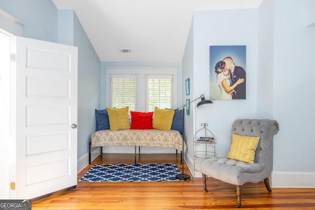 sitting room with visible vents, baseboards, lofted ceiling, and wood finished floors