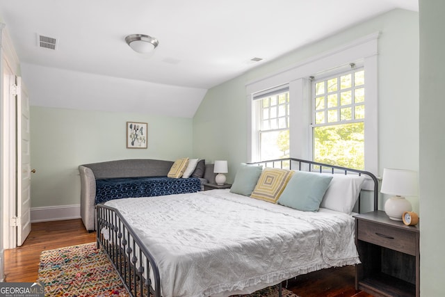 bedroom featuring visible vents, baseboards, lofted ceiling, and wood finished floors