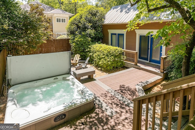 wooden deck featuring a covered hot tub and fence