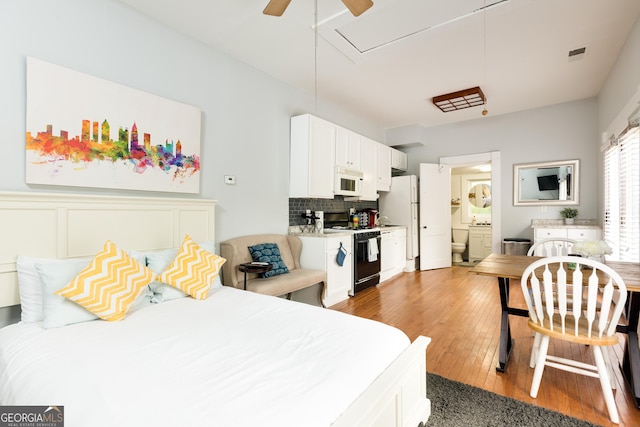 bedroom featuring ensuite bath, freestanding refrigerator, visible vents, and light wood finished floors