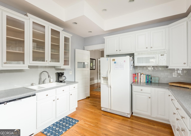 kitchen featuring light wood-style flooring, a sink, white appliances, white cabinets, and light countertops