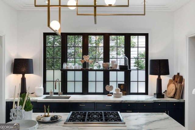 kitchen featuring dark cabinets, crown molding, stainless steel gas cooktop, and a sink