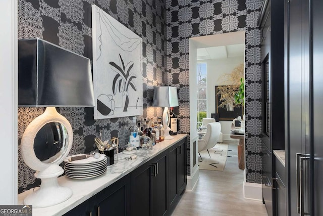 bathroom featuring wallpapered walls, double vanity, and wood finished floors