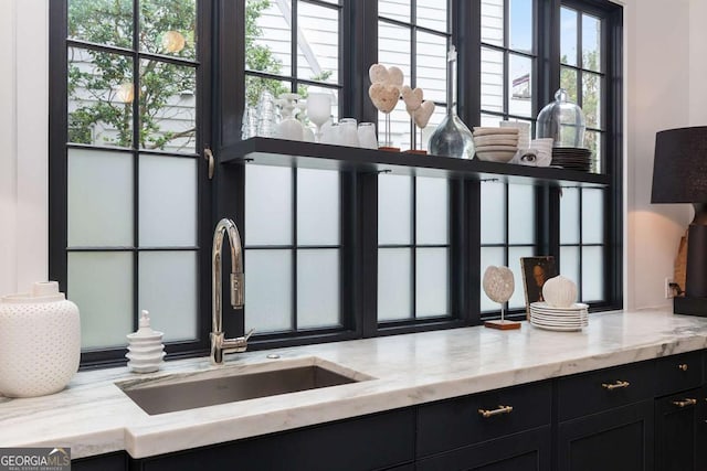 interior details featuring light stone countertops, dark cabinets, and a sink