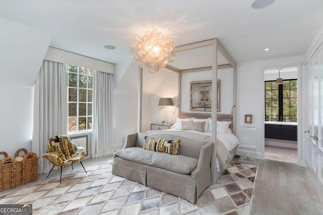 bedroom featuring multiple windows, wood finished floors, a wainscoted wall, and a chandelier