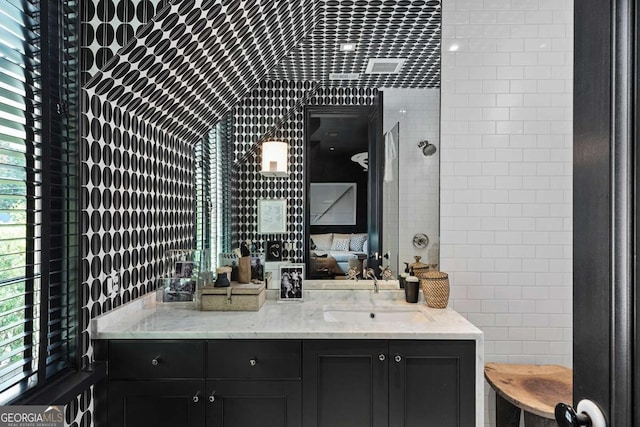 ensuite bathroom with vanity, tile walls, a healthy amount of sunlight, and ensuite bathroom