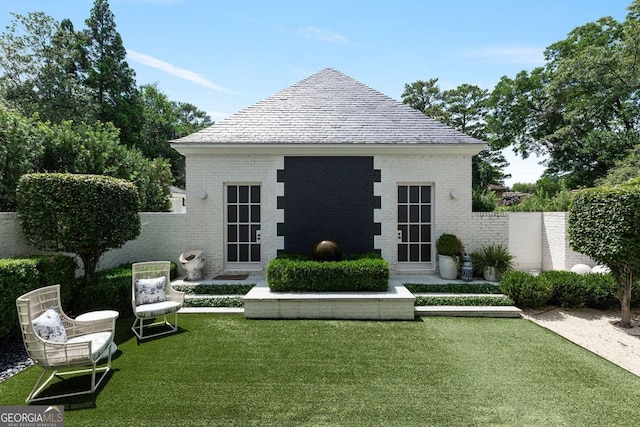 back of house with a yard, fence, and brick siding