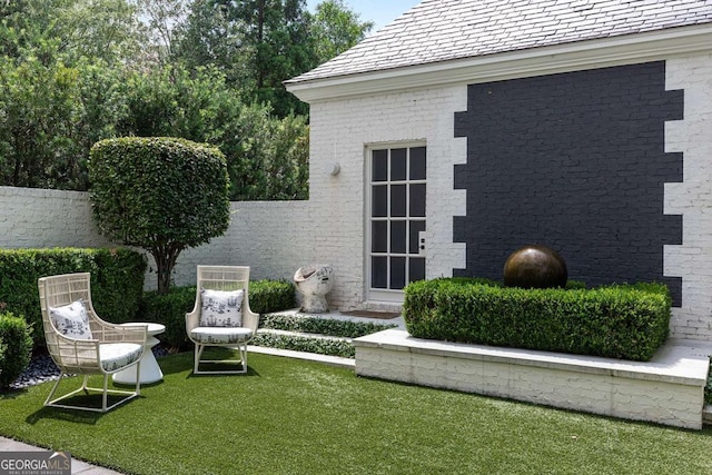 exterior space with a high end roof, fence, a lawn, and brick siding