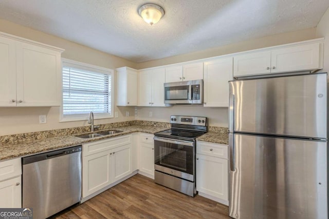 kitchen with a sink, stainless steel appliances, dark wood-style floors, and white cabinets