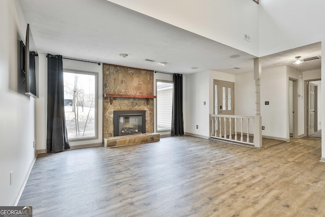 unfurnished living room with light wood finished floors, visible vents, a fireplace, and baseboards