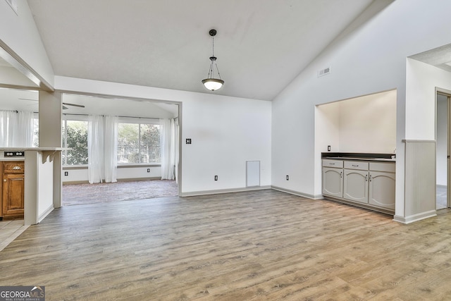 unfurnished living room featuring visible vents, light wood-style flooring, high vaulted ceiling, and baseboards