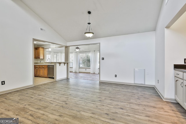 unfurnished living room featuring light wood-style floors, baseboards, and high vaulted ceiling