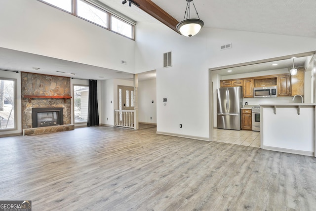 unfurnished living room featuring plenty of natural light, a fireplace, and visible vents