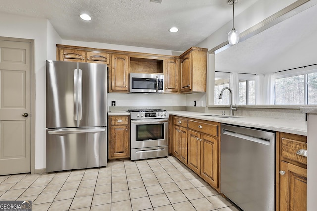 kitchen featuring brown cabinetry, appliances with stainless steel finishes, light countertops, and a sink