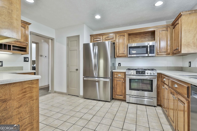 kitchen featuring light countertops, light tile patterned floors, brown cabinetry, and appliances with stainless steel finishes