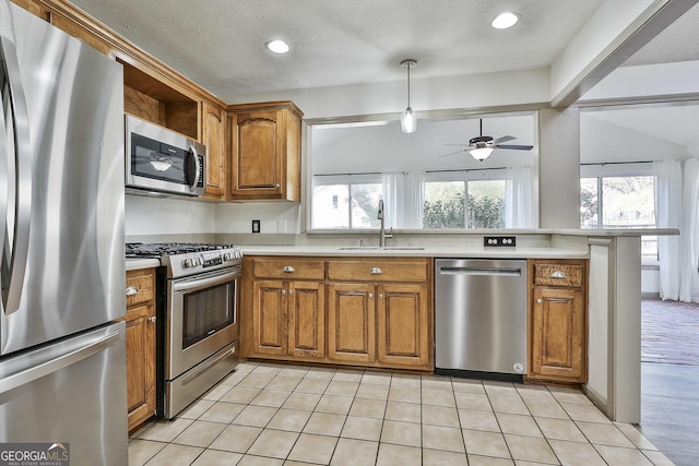 kitchen with brown cabinetry, a healthy amount of sunlight, stainless steel appliances, and a sink