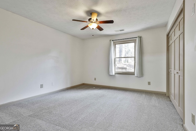 unfurnished bedroom with visible vents, a ceiling fan, a textured ceiling, baseboards, and light colored carpet