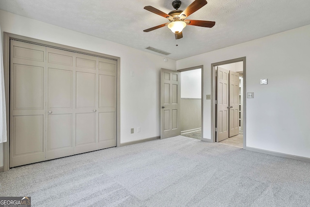 unfurnished bedroom with visible vents, baseboards, light colored carpet, a closet, and a textured ceiling