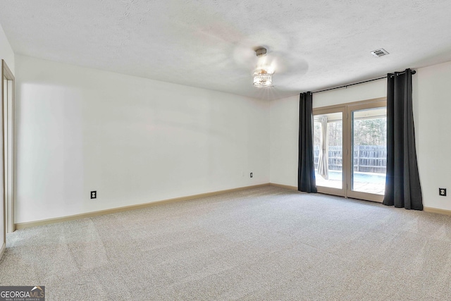 empty room with visible vents, light colored carpet, a textured ceiling, and baseboards