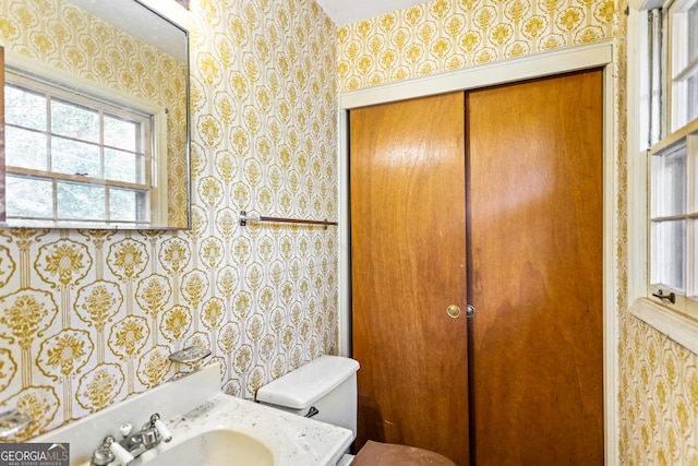 bathroom with wallpapered walls, toilet, and vanity