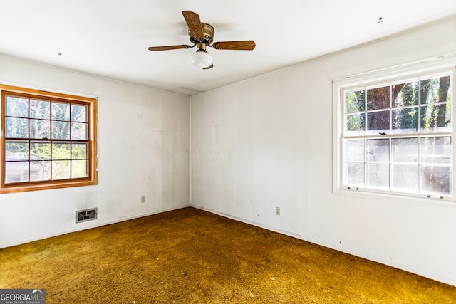 empty room featuring visible vents, a healthy amount of sunlight, and a ceiling fan