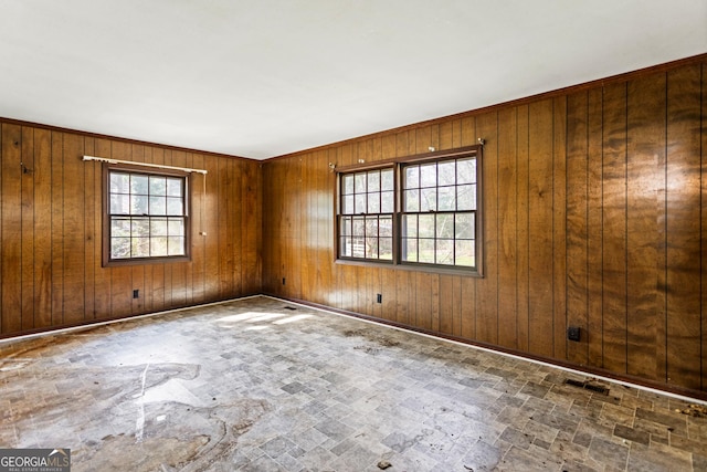 unfurnished room featuring visible vents, wood walls, and stone finish flooring