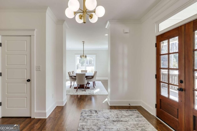 foyer with a chandelier, dark wood finished floors, baseboards, and ornamental molding