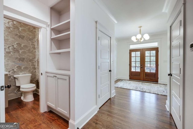 foyer entrance featuring dark wood-style floors, a notable chandelier, french doors, and baseboards