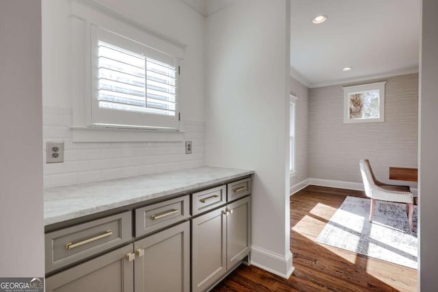 interior space featuring tasteful backsplash, dark wood-type flooring, baseboards, light stone countertops, and recessed lighting