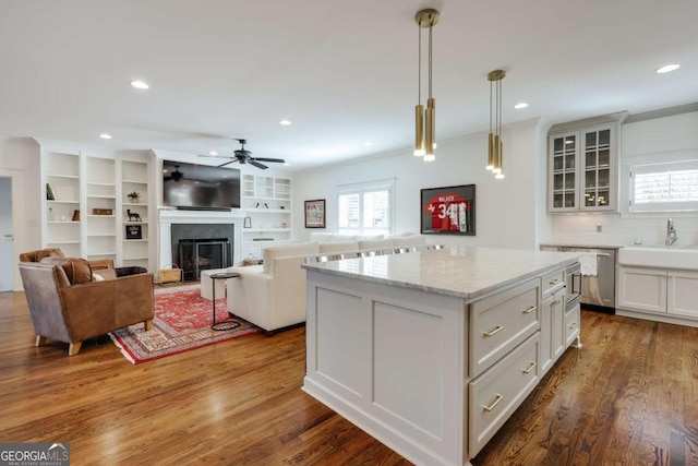 kitchen with a sink, dark wood finished floors, white cabinetry, a fireplace, and glass insert cabinets