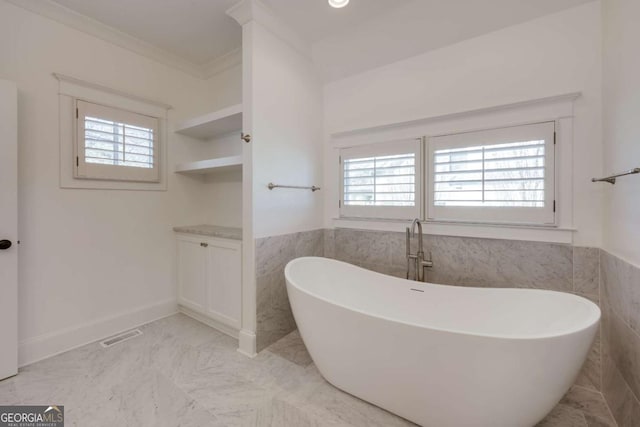 full bath with a wealth of natural light, visible vents, crown molding, and a freestanding tub