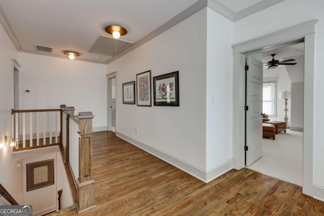 hallway featuring visible vents, an upstairs landing, attic access, and wood finished floors