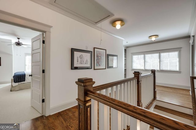 hallway featuring baseboards, an upstairs landing, attic access, and dark wood-style floors