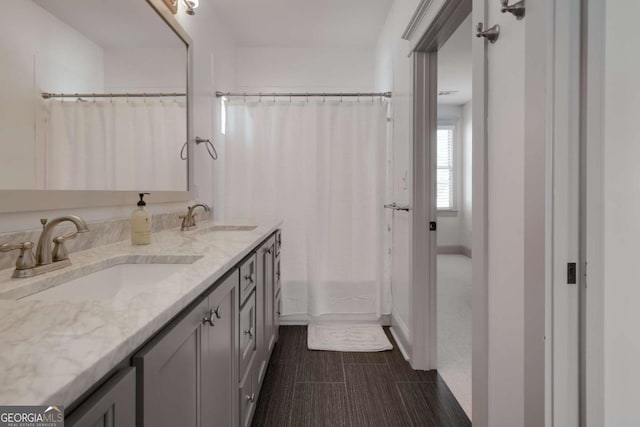 bathroom with double vanity, baseboards, and a sink