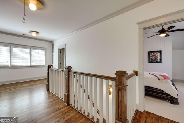 hall with visible vents, an upstairs landing, ornamental molding, wood finished floors, and baseboards