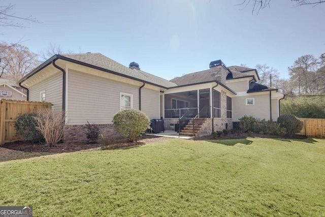 rear view of house featuring a lawn, fence, a sunroom, brick siding, and a chimney