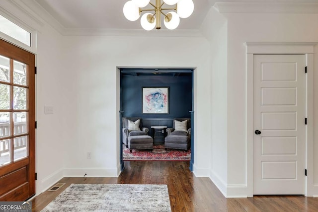 foyer with crown molding, wood finished floors, visible vents, and a chandelier