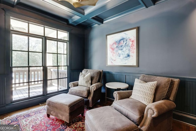 living area with beamed ceiling, wainscoting, coffered ceiling, and wood finished floors