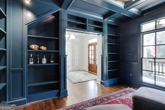 interior space with built in shelves, beam ceiling, coffered ceiling, wood finished floors, and french doors