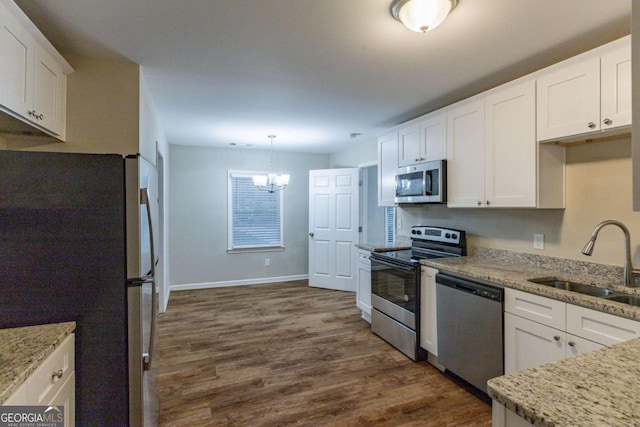 kitchen with a sink, appliances with stainless steel finishes, white cabinets, an inviting chandelier, and dark wood-style flooring