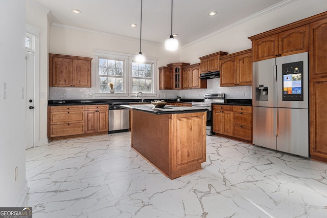kitchen featuring brown cabinets, marble finish floor, under cabinet range hood, dark countertops, and stainless steel appliances